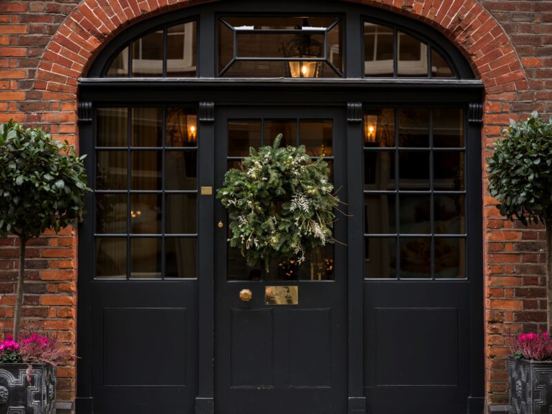 Festive wreath on the black Georgian front door of Batty Langley’s, framed by red brick and topiary plants.